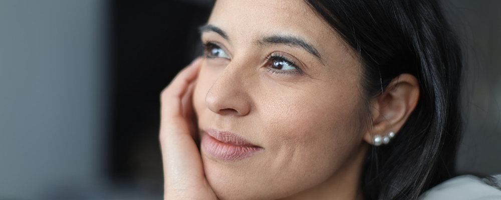 Businesswoman holding chin, thinking and looking up with hope